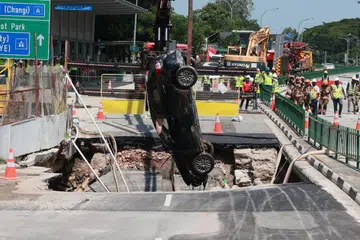 DISELAMATKAN: Pemandu wanita itu berada dalam keadaan sedar ketika dibawa ke Hospital Raffles dan kereta yang dipandunya dikeluarkan daripada lubang benam yang terbentuk di Tanjong Katong Road pada 26 Julai.