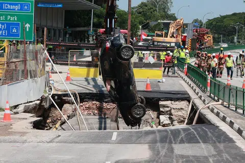 DISELAMATKAN: Pemandu wanita itu berada dalam keadaan sedar ketika dibawa ke Hospital Raffles dan kereta yang dipandunya dikeluarkan daripada lubang benam yang terbentuk di Tanjong Katong Road pada 26 Julai.