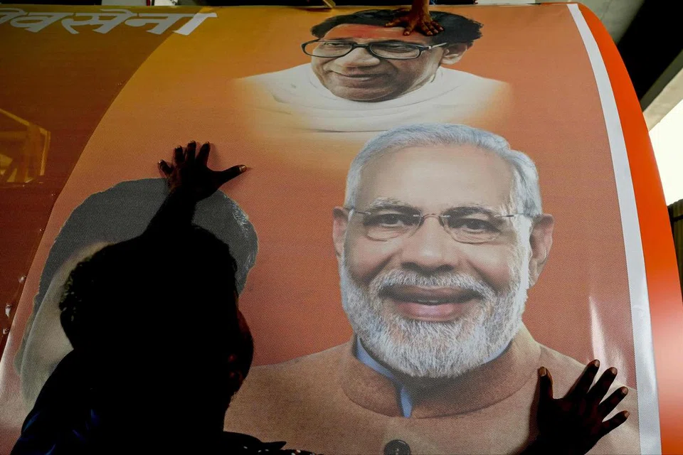 Pekerja memasang pelekat dengan gambar pemimpin Parti Bharatiya Janata (BJP) dan Perdana Menteri India, Encik Narendra Modi (kanan), pada kenderaan semasa kempen pilihan raya di Mumbai pada 27 April.