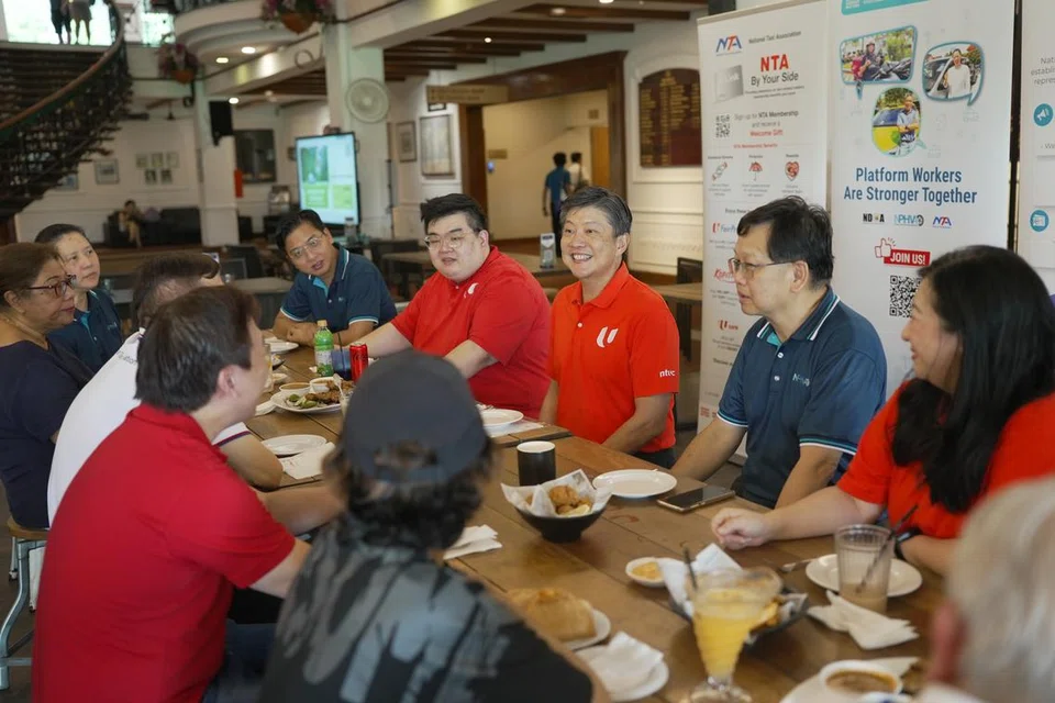 MANFAAT PEKERJA: Setiausaha Agung NTUC, Encik Ng Chee Meng (duduk kanan tengah) bertemu pekerja platform termasuk pekerja penghantaran, pemandu teksi dan PHV di Orchid Country Club sewaktu pelancaran Skim Dana Penjagaan NTUC (Bantuan Kecederaan Tempat Kerja) pada 6 Disember.