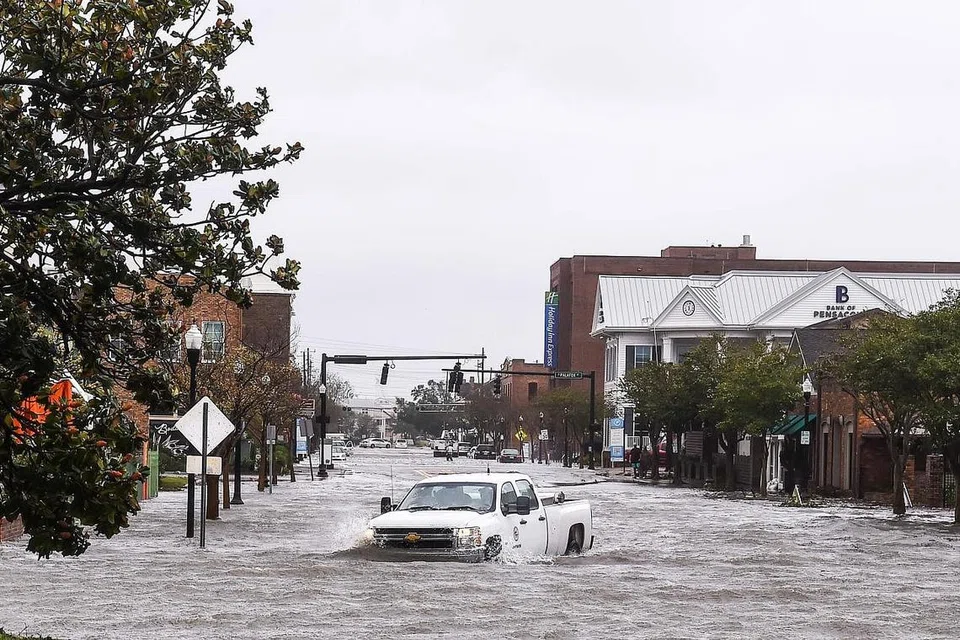 HAMPIR KARAM: Sebuah bot hampir tenggelam dan dimasuki air setelah kawasan Pensacola, Florida, dilanda Taufan Sally. (Gambar atas) Seorang pemandu sedang meredah banjir di bandar Pensacola, Florida. - Foto-foto REUTERS, AFP