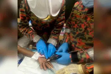 Anggota bomba membantu tanggalkan  cincin yang tersekat pada jari tengah tangan kiri seorang lelaki di Klinik Kesihatan Jeniang, Kedah.
