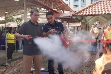 Profesor Madya Dr Muhammad Faishal Ibrahim (kiri) di acara Akar Umbi Masyarakat di Nee Soon Central di mana penduduk diajar cara menggunakan alat pemadam api. 