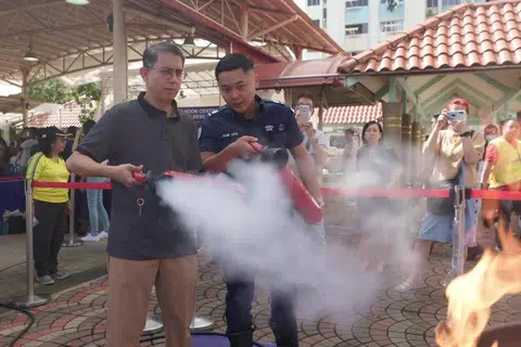 Profesor Madya Dr Muhammad Faishal Ibrahim (kiri) di acara Akar Umbi Masyarakat di Nee Soon Central di mana penduduk diajar cara menggunakan alat pemadam api. 