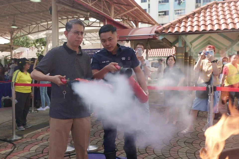 Profesor Madya Dr Muhammad Faishal Ibrahim (kiri) di acara Akar Umbi Masyarakat di Nee Soon Central di mana penduduk diajar cara menggunakan alat pemadam api. 