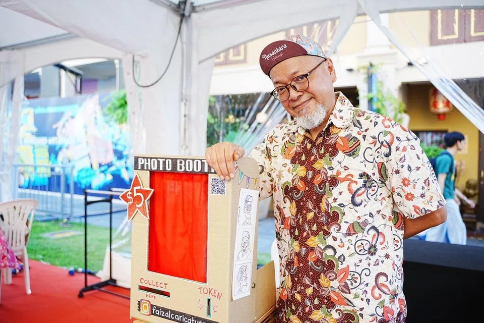 Faizal A Bakar, 58 tahun, menawarkan khidmat lukisan karikatur untuk pelanggannya dengan harga $5. Lukisan itu kemudian ‘dikeluarkan’ dari reruai foto klasik buatannya sendiri. 