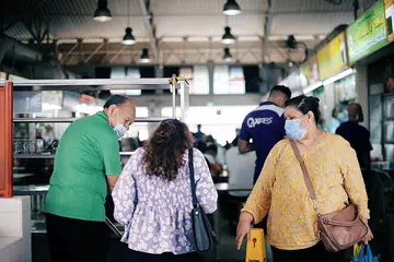 PATUHI PERATURAN: Cik Zarah Mohamed Kassim, 55 tahun dan anaknya, Cik Ruhaya Hendri, 26 tahun mengembalikan dulang dan pinggan mangkuk mereka di pusat penjaja Haig Road semalam. - Foto BH oleh HARITH MUSTAFFA