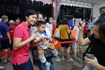 Anggota Parti Tindakan Rakyat (PAP), Cik Deryne Sim (kiri) bersama penduduk pada acara pelancaran sambutan Tahun Baru Cina ‘Springtime Splendour@Nee Soon’ anjuran Persatuan Rakyat (PA) bagi menandakan permulaan Tahun Baru Cina di padang terbuka bersebelahan Kolam Yishun.