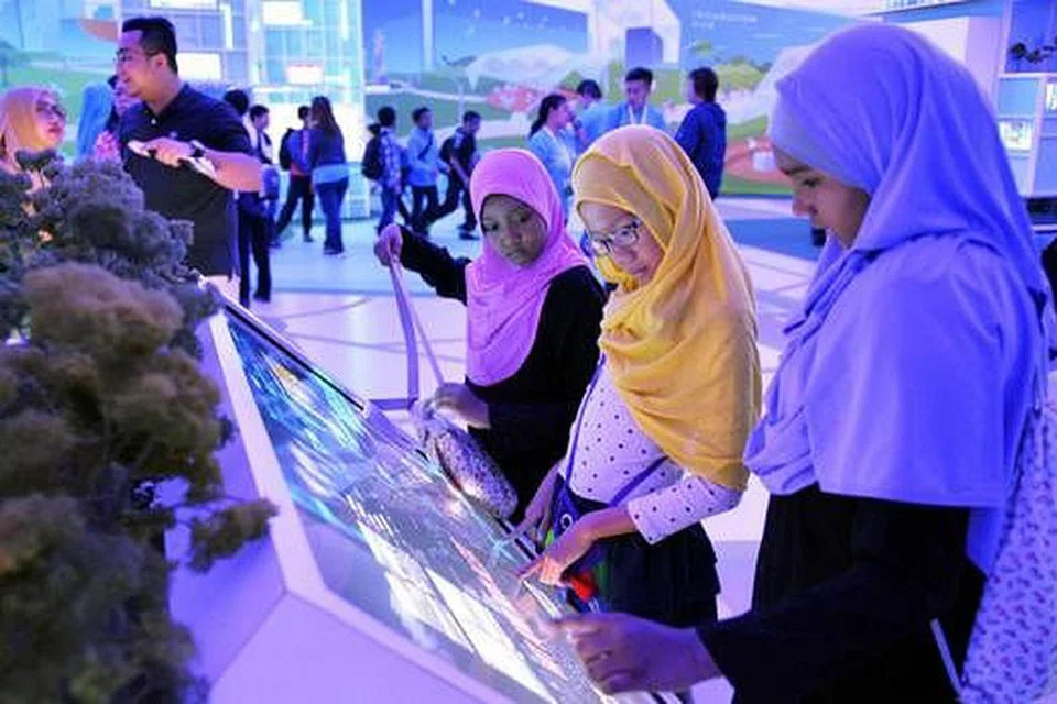 TIMBA ILMU DI PAMERAN: Aneesah Eiliyah Chan (dua dari kanan) seronok mempelajari tentang masa depan Singapura dan warga serta langkah yang boleh diambil hari ini bagi memastikan generasi akan datang dapat menjalani kehidupan yang selesa. - Foto KHALID BABA