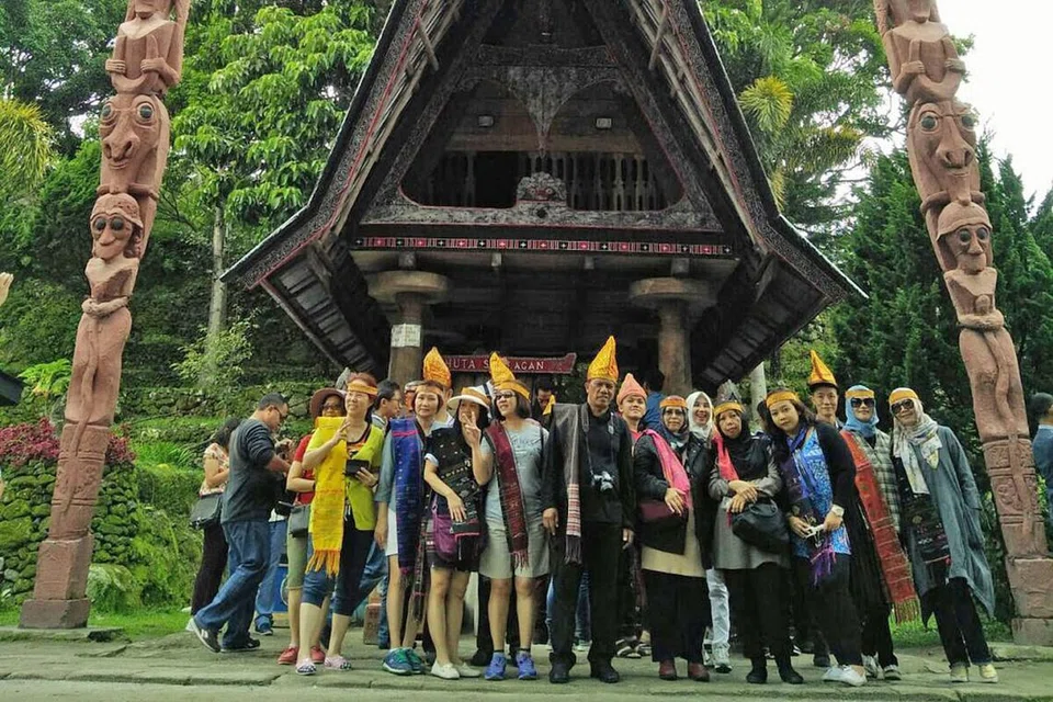 KAYA DENGAN BUDAYA: Wartawan (tengah berbaju dan seluar hitam) bergambar bersama pelancong di hadapan rumah tradisional Batak di Pulau Samosir, Danau Toba. - Foto-foto oleh Saini Salleh