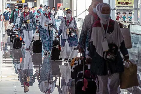 BERANGKAT: Sebahagian daripada kumpulan pertama jemaah haji Indonesia yang berlepas dari Lapangan Terbang Antarabangsa Juanda di Surabaya pada 4 Jun. Semua jemaah akan diberi beg berisi peralatan kesihatan seperti pelitup dan sanitasi tangan. - Foto AFP