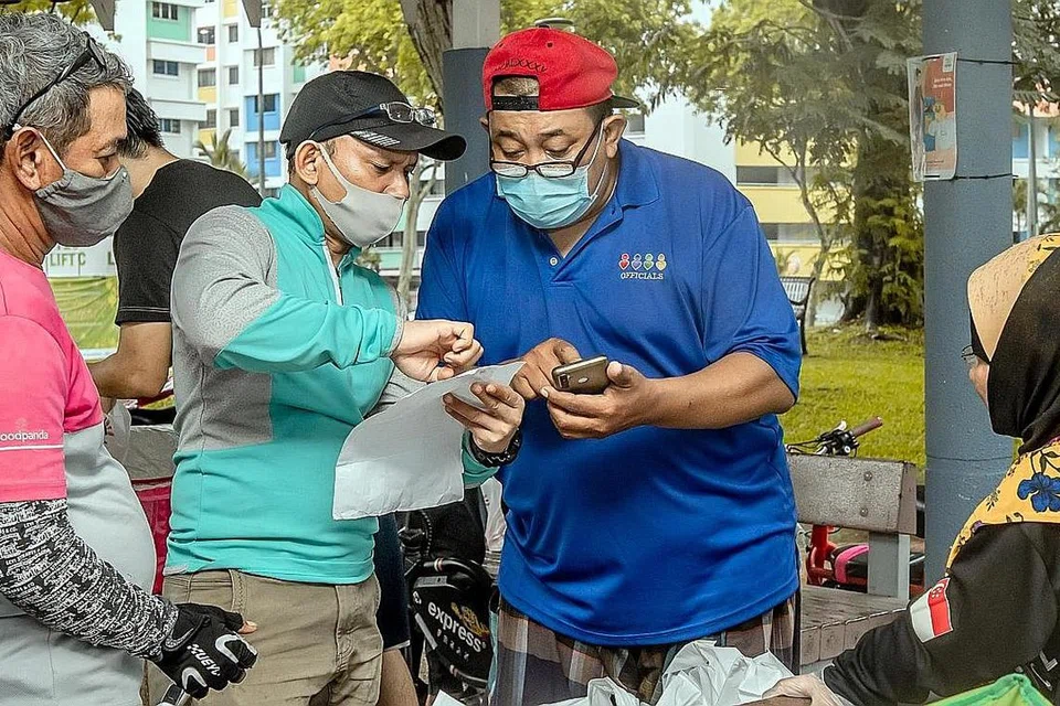 INGIN MEMBALAS BUDI: Encik Shamsuri Jumadi (memakai topi merah) dilihat sedang menyelia usaha pengagihan habuan Ramadan di Yishun Street 71 bersama para pekerja penghantaran makanan. - Foto BH oleh NUR DIYANA TAHA