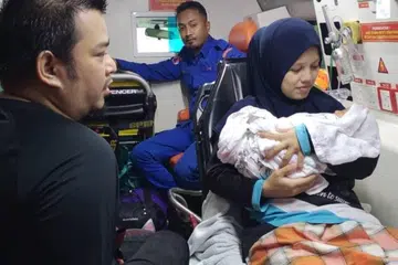 BANTUAN SEGERA: Anggota Angkatan Pertahanan Awam Malaysia (APM) membantu pasangan membawa bayi mereka yang baru lahir untuk ke Klinik Kesihatan Seri Langkap, Setiu, Terengganu, selepas jalan raya di kawasan penempatan mereka di Kampung Kasar dinaiki air akibat banjir.