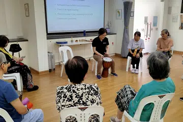 Ahli Terapi Muzik 365 Cancer Prevention Society (365CPS), Cik Germaine Yong (tengah), mengendalikan sesi terapi muzik berkumpulan menggunakan alat muzik genderang.