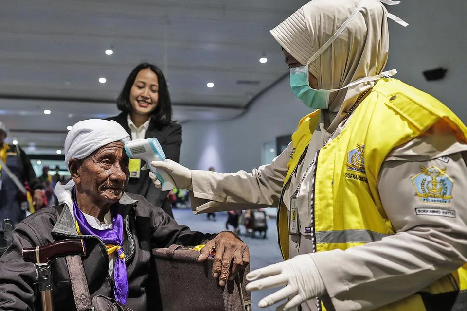 TINGKAT PENGAWASAN: Seorang pegawai kuarantin kesihatan Indonesia mengambil suhu seorang penumpang yang baru tiba di Lapangan Terbang Antarabangsa Soekarno-Hatta di Tangerang di pinggir bandar Jakarta semalam. - Foto EPA-EFE