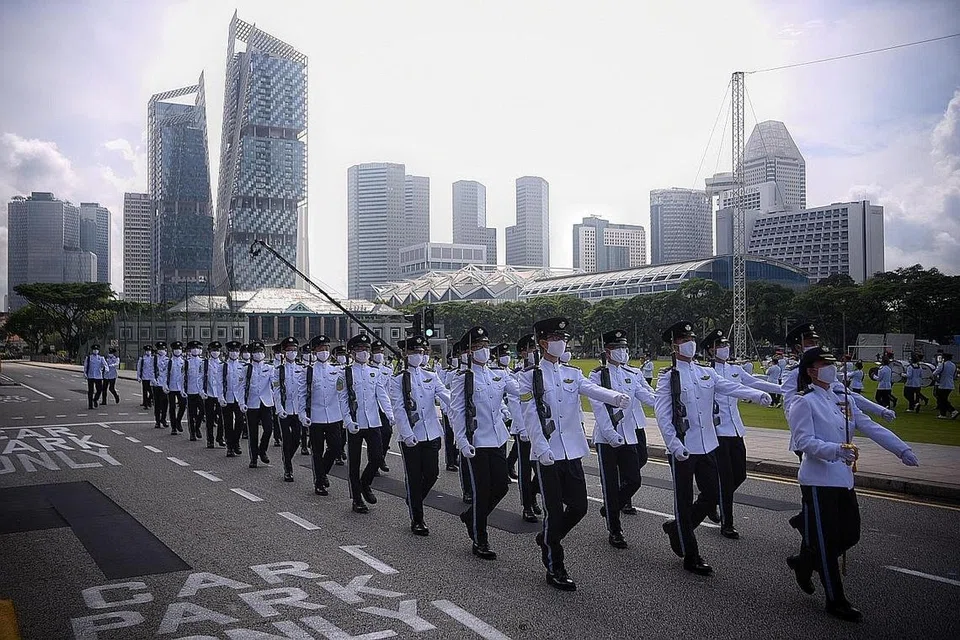 BERSKALA KECIL: Perbarisan berskala kecil dengan setiap kontinjen mempunyai 36 peserta iaitu separuh berbanding tahun-tahun lalu dek langkah jarak selamat yang diadakan bersama dengan Tembak Hormat Presiden di Padang pada segmen pagi sambutan Hari Kebangsaan. - Foto-foto BH oleh MARK CHEONG 