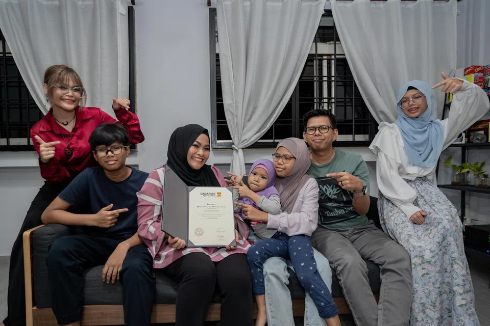 KEBANGGAAN KELUARGA: Cik Sazzuria Hashim (tiga dari kiri) berjaya muncul Valedictorian Kelas 2023 Politeknik Singapura. Bersamanya ialah suami, Encik Muhammad Firdaus Zainal Abidin (dua dari kanan), dan anak-anak (dari kiri) Nur Syahirah, Shaaz Firas, Myeisha, Zaheen Alveena serta Faiqah Sumayyah.