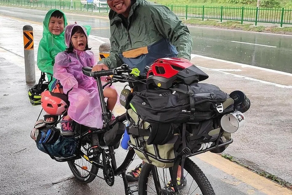 TETAP SERONOK: Encik Rezal sekeluarga meredah hujan sewaktu pengembaraan mereka meneroka Singapura.
