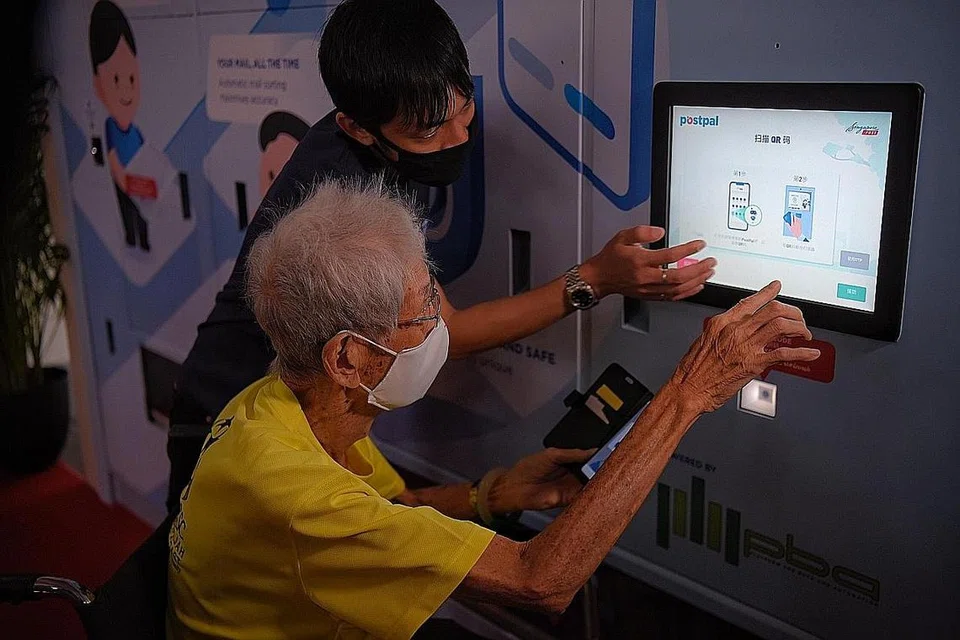 TUNJUK CARA GUNA: Encik Jovan Lim, pengurus kanan SingPost, membantu Encik Chee Fook Chow, penduduk berusia 90 tahun, cara menggunakan sistem peti surat bijak di Blok 202 Clementi Avenue 6 semalam. - Foto BH oleh MARK Cheong