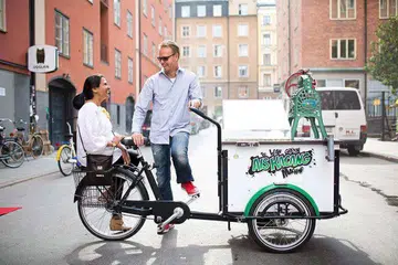Encik Nic Ribbarp dan isterinya Cik Vas Ribbarp bergambar di kota Sweden dengan mesin ais kacang dan basikal tiga rodanya. 