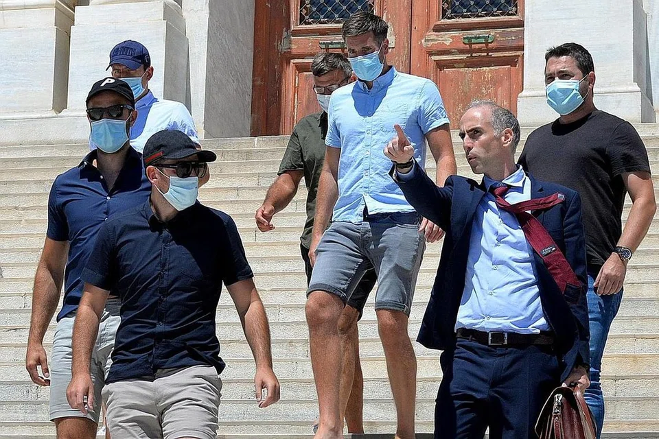 DIBICARA: Harry Maguire (atas kiri, bertopi biru) meninggalkan bangunan mahkamah di pulau Syros, di Greece, dengan peguamnya, Encik Costantine Darivas. - Foto EPA-EFE