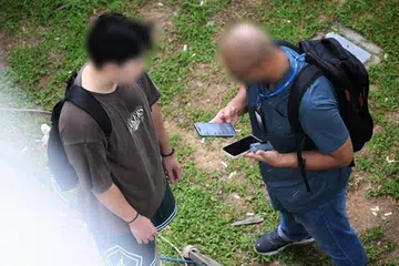 Seorang pegawai HSA (kanan) merampas ‘vape’ daripada seorang pelajar di Tampines pada 14 Julai.
