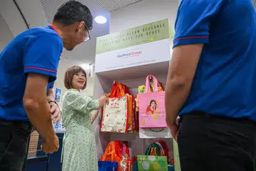 SEDIAKAN BEG GUNA SEMULA: Menteri Negara Kanan (Kemampanan dan Sekitaran merangkap Pengangkutan), Dr Amy Khor (tengah), melihat inisiatif rak beg yang disediakan pasar raya FairPrice.