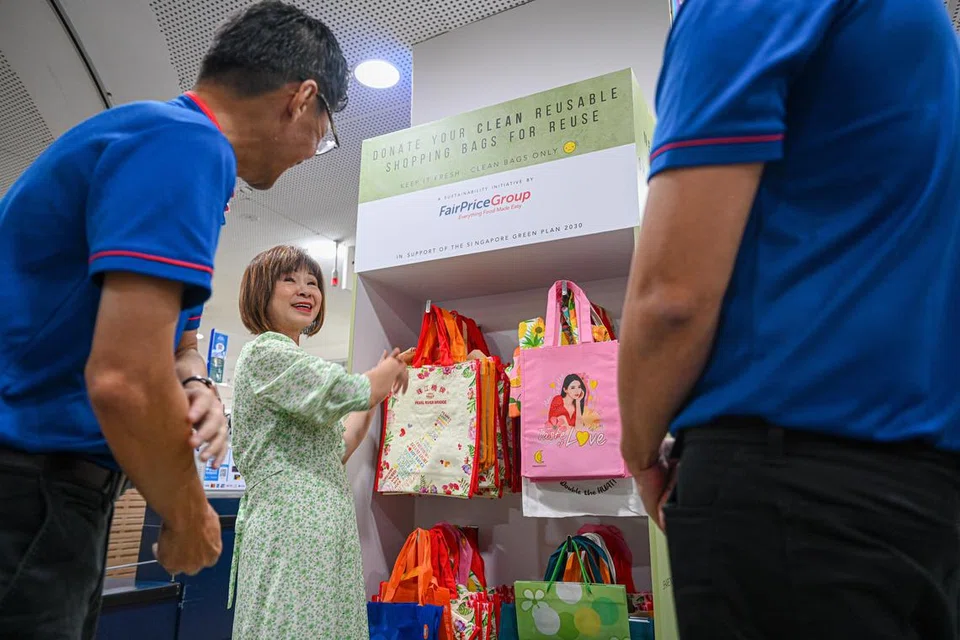 SEDIAKAN BEG GUNA SEMULA: Menteri Negara Kanan (Kemampanan dan Sekitaran merangkap Pengangkutan), Dr Amy Khor (tengah), melihat inisiatif rak beg yang disediakan pasar raya FairPrice.