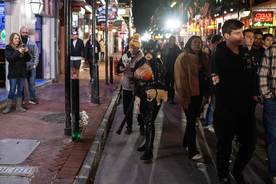 Orang ramai berjalan melewati jambangan bunga yang diletak di Bourbon Street di French Quarter, New Orleans, pada 2 Januari, bagi memperingati mangsa satu serangan maut di situ sehari sebelumnya. Seramai 14 orang terkorban apabila seorang tentera veteran Amerika Syarikat merempuh hadirin dalam pesta sambutan Tahun Baru di situ dengan sebuah trak.