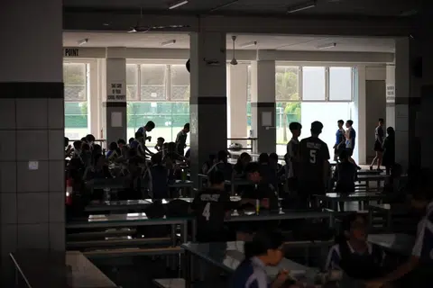 Pelajar Sekolah Menengah Jurong West menjamu selera dalam malap ketika waktu rehat di kantin sekolah semasa simulasi bekalan tenaga elektrik terputus.