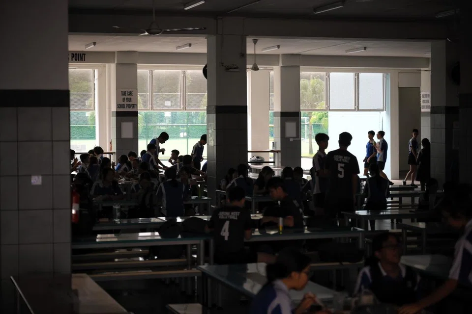 Pelajar Sekolah Menengah Jurong West menjamu selera dalam malap ketika waktu rehat di kantin sekolah semasa simulasi bekalan tenaga elektrik terputus.