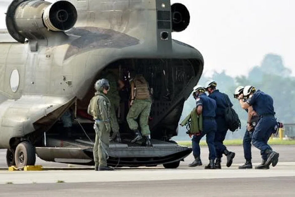 HULUR BANTUAN: Pegawai SAF dan SCDF menaiki helikopter Chinook untuk ke Indonesia semalam. - Foto MINDEF