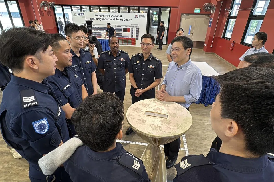 Perdana Menteri Lawrence Wong (berkemeja biru air) beramah-tamah bersama para pegawai SPF dan SCDF semasa melawat Pusat Polis Kejiranan Punggol dan Balai Bomba Punggol pada 4 April. 
