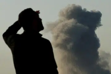 Seorang tentera Israel berlatar asap tebal yang menjulang di Beit Hanoun, Gaza, di tengah-tengah konflik yang berterusan antara Israel dengan Hamas, seperti yang kelihatan dari selatan Israel, pada 8 Januari.