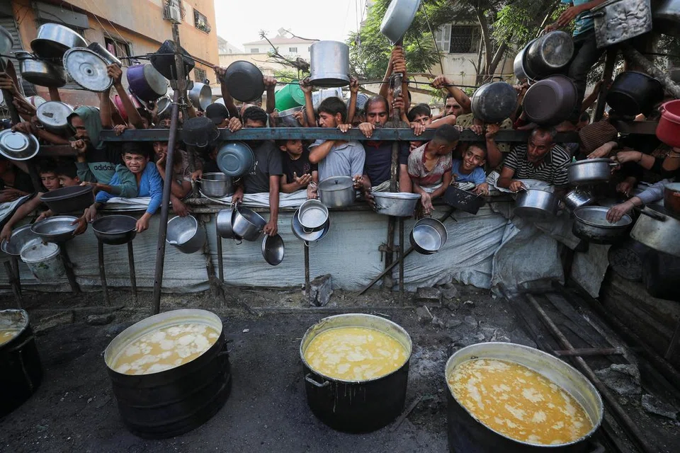 Penduduk Palestin menunggu untuk menerima makanan daripada dapur amal ketika krisis kebuluran berterusan di Bandar Gaza, 14 Julai 2025.