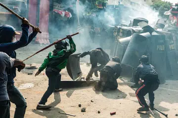 Orang ramai bertempur dengan anggota pengawal rusuhan Korps Brigade Mobil, atau ‘Brimob’, di tengah-tengah awan gas pemedih mata, semasa rusuhan berikutan kematian seorang pemandu teksi motosikal pada malam sebelumnya, di hadapan ibu pejabat Brimob di Jakarta pada 29 Ogos 2025.