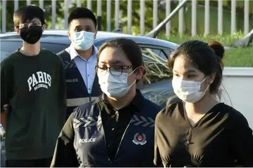 Pansuk Siriwipa (kanan) diiring pegawai polis Singapura di Pusat Pemeriksaan Woodlands pada 11 Ogos 2022.