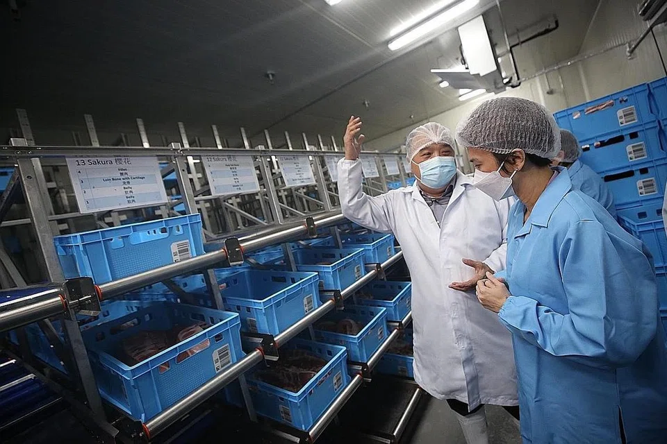 HURAIAN DIGITAL DI KILANG MAKANAN: Menteri Negara Perdagangan dan Perusahaan Low Yen Ling (kanan) mendengar taklimat daripada pengarah urusan Tiong Lian Food Pte Ltd, Encik Benson Teo, mengenai huraian digital dan automasi yang digunakan kilang tersebut. - Foto BH oleh TIMOTHY DAVID