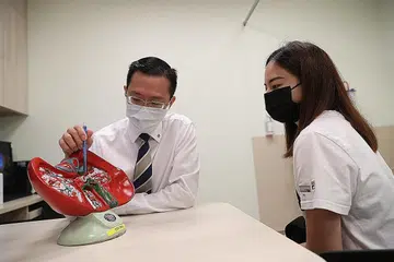 LEBIH RAMAI DIHARAP BANTU: Profesor Alfred Kow menunjukkan model hati kepada seorang penderma, Cik Sophia Chua. Dengan prosedur baru itu, diharapkan lebih ramai orang membantu pesakit memerlukan hati. - Foto BH oleh TIMOTHY DAVID