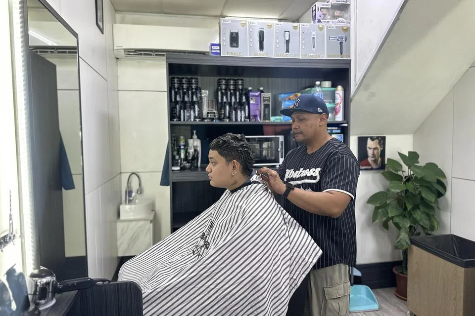Menurut Encik Muhammad Syuhadak Surhan (kanan), perniagaan gunting rambutnya, Albatross Barbershop, di 57 Marine Terrace, kini menarik lebih ramai pelanggan Gen Z.