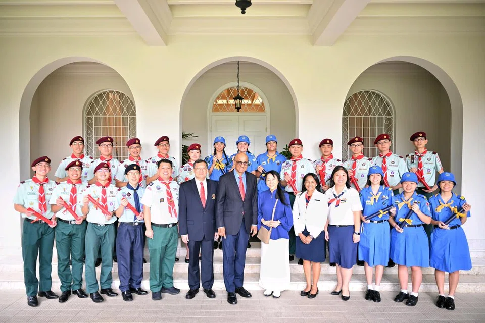 Presiden Tharman Shanmugaratnam (tujuh dari kiri) dan isterinya, Puan Jane Ittogi (enam dari kanan), bergambar bersama penerima anugerah Pengakap dan Pandu Puteri di Istana pada 2 Disember.