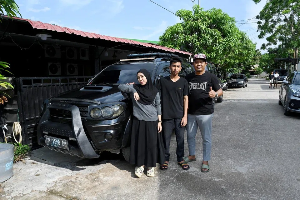 (Dari kiri) Encik Shaiful Saad, isteri Cik Nia Tutira dan anak mereka Syahputra Ergian, bergambar di luar rumah kediaman mereka di Tiban, salah satu kawasan yang didiami ramai warga Singapura di Batam.