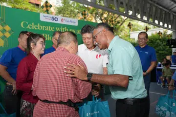 (Dari kanan) Penasihat Pertubuhan Akar Umbi (GRO) Bukit Batok, Encik Murali Pillai dan Setiausaha Agung Kongres Kesatuan Sekerja Kebangsaan, Encik Ng Chee Meng mengagihkan hamper kepada Encik Senin Ahmad (membelakang kamera) sempena acara ‘Block Party’ anjuran FairPrice Group pada 20 April.