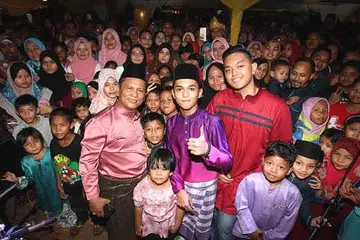 MENARIK PEMINAT: Aiman Tino (baju kurung ungu) bergambar bersama peminat yang hadir di rumah terbuka yang diadakan di Dataran Kuala Kubu Bharu, Selangor. - Foto BERITA HARIAN MALAYSIA