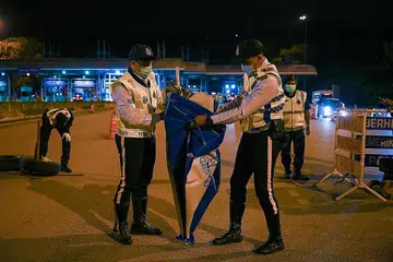 SIAP BUBAR SEKATAN: Para pegawai polis berkemas untuk membuka semula jalan di Lebuhraya Pantai Timur (Kuala Lumpur-Karak) di Bentong, Pahang malam kelmarin selepas rentas sempadan dibenarkan mulai semalam. - Foto AFP