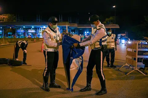 SIAP BUBAR SEKATAN: Para pegawai polis berkemas untuk membuka semula jalan di Lebuhraya Pantai Timur (Kuala Lumpur-Karak) di Bentong, Pahang malam kelmarin selepas rentas sempadan dibenarkan mulai semalam. - Foto AFP