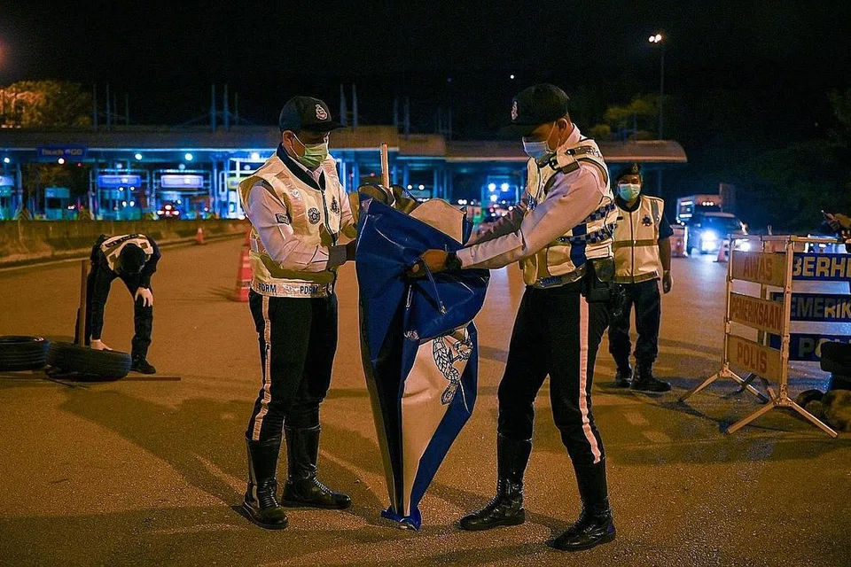 SIAP BUBAR SEKATAN: Para pegawai polis berkemas untuk membuka semula jalan di Lebuhraya Pantai Timur (Kuala Lumpur-Karak) di Bentong, Pahang malam kelmarin selepas rentas sempadan dibenarkan mulai semalam. - Foto AFP