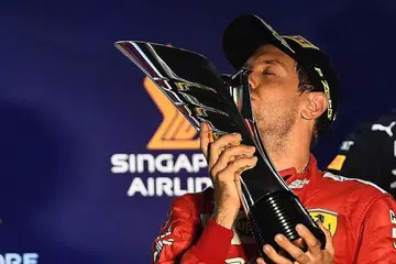 KEMENANGAN MANIS: Vettel mencium piala kemenangan Grand Prix Singapura kelimanya. Pemandu Red Bull Max Verstappen (tiada dalam gambar) mengakhiri perlumbaan di posisi ketiga. - Foto BH oleh EPA-EFE.