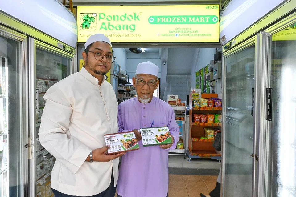 (Dari kiri) Pengarah Urusan Pondok Abang, Encik Hasan Abdul Rahman bersama Eksekutif Pembangun Perniagaan, Haji Muhd Wahid Suyod memegang dua makanan sejuk beku tradisional Melayu Pondok Abang yang popular dalam kalangan pelanggan Melayu/Islam, iaitu rendang daging dan ayam.