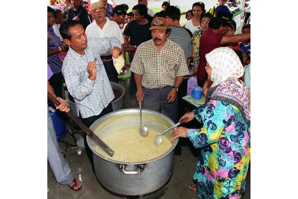 TAMPINES: Mantan Setiausaha Parlimen Kanan, Encik Yatiman Yusof (kiri), membantu mengikat bungkusan plastik berisi bubur selaku tetamu kehormat bersama beberapa relawan di Sudut Warga Tua di Blok 924, Tampines Street 91, dalam majlis perasmian projek menyediakan bubur pada 1998.